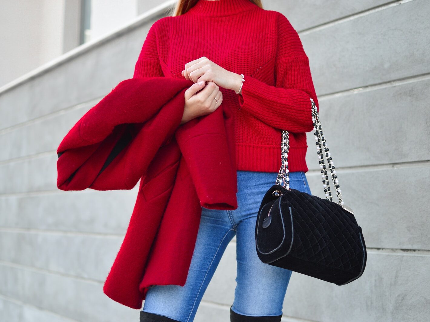 woman in red sweater beside white wall