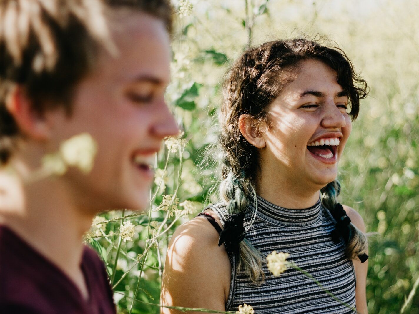 man and woman laughing surrounded with green grass during daytime