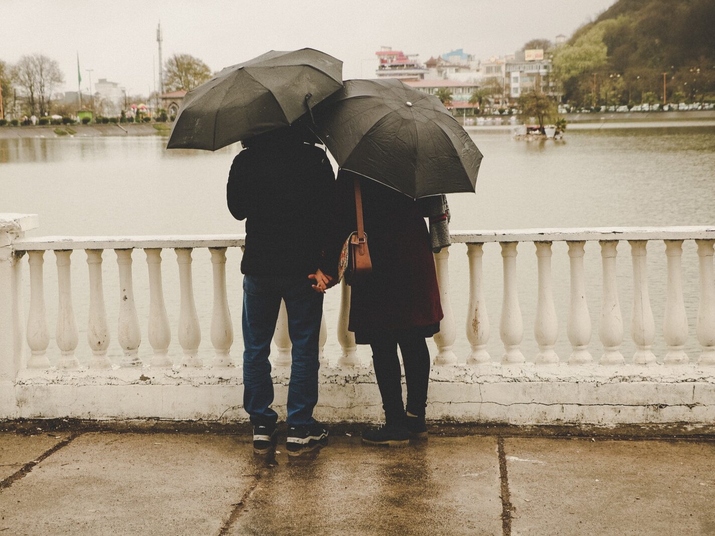 man and woman holding black umbrellas