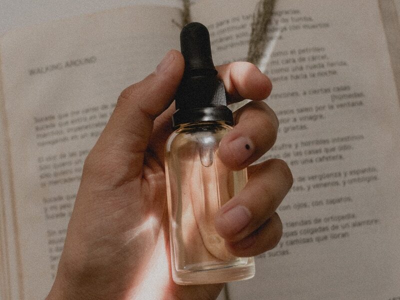 person holding small clear drop bottle