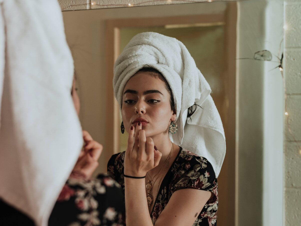 woman putting makeup in front of mirror