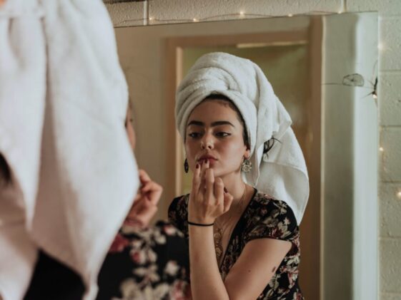 woman putting makeup in front of mirror