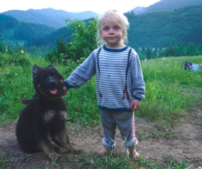 girl wearing blue striped shirt beside black dog
