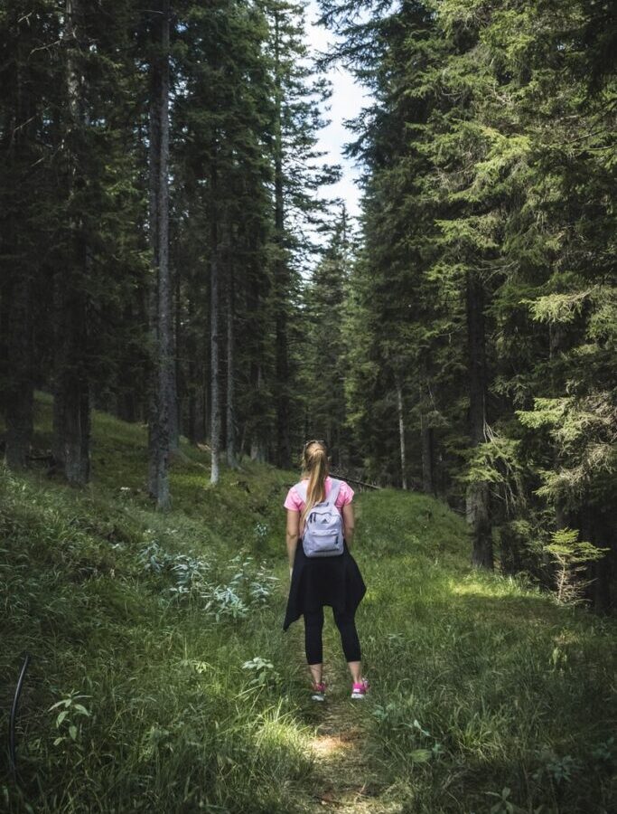 woman carrying backpack on forest