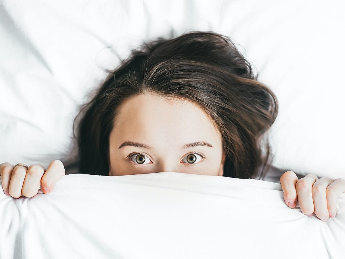 woman covering her face with blanket