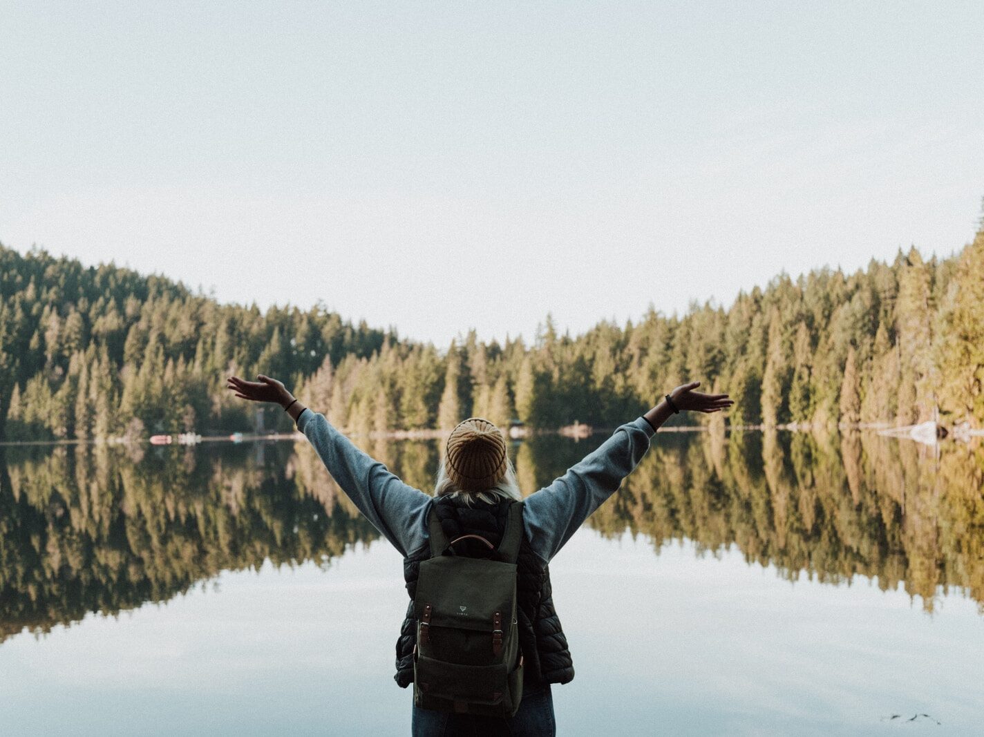 woman open her arms facing calm body of water