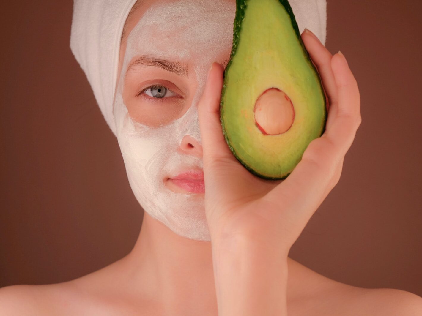 woman with white face mask holding green fruit