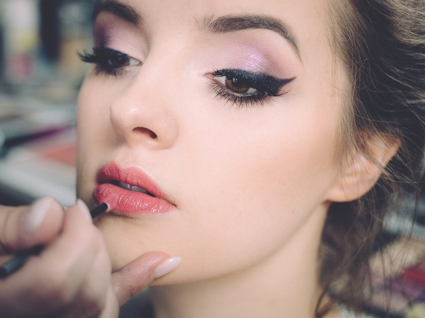 woman getting lips applied with lipstick