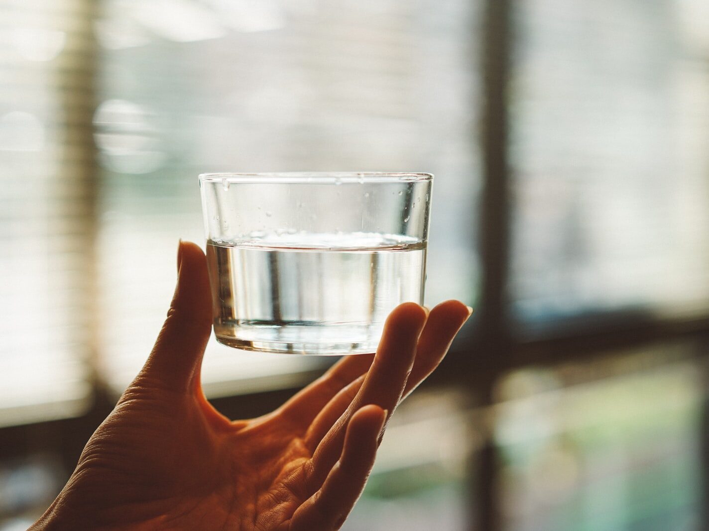 person holding clear glass cup with half-filled water