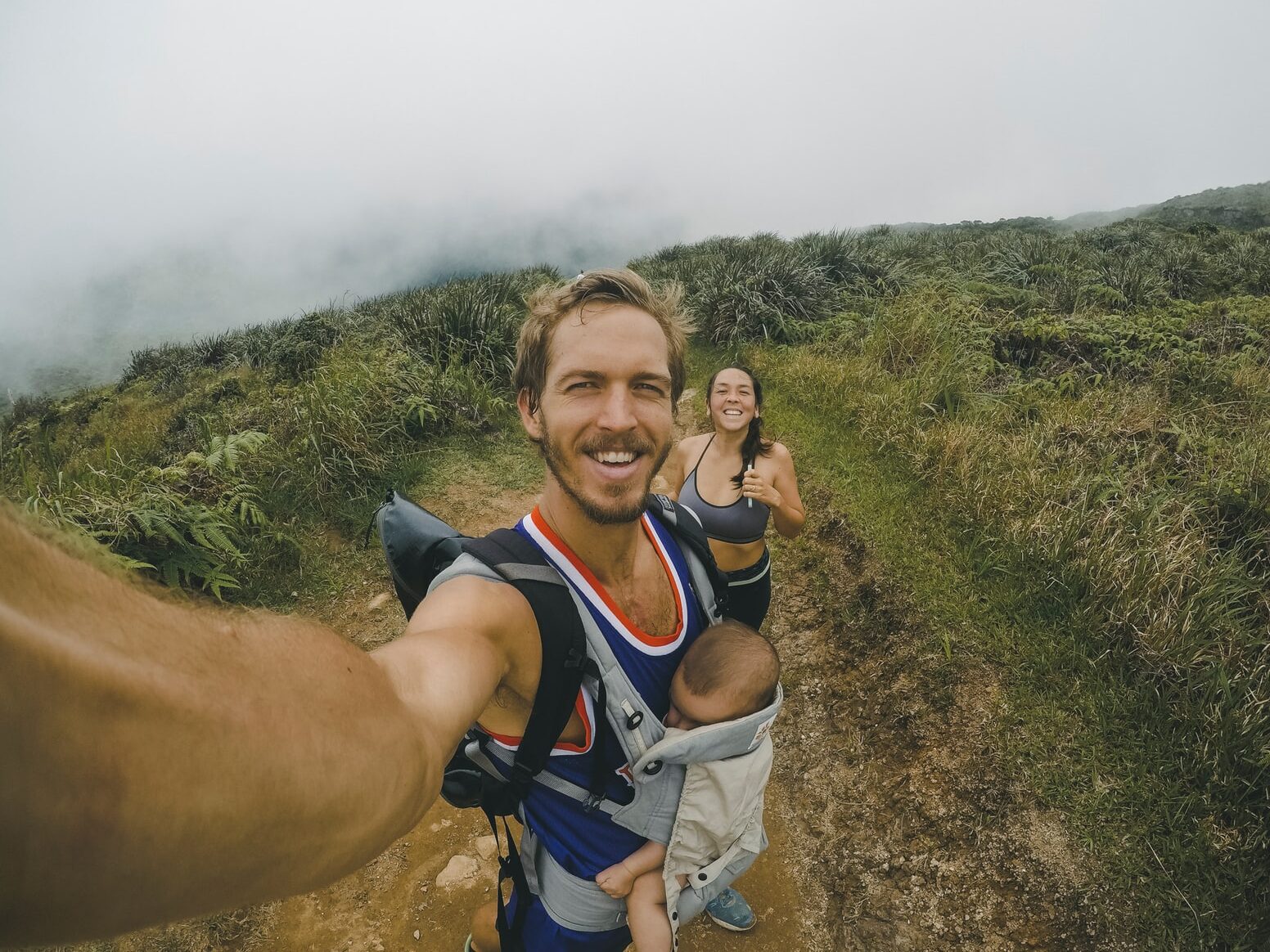 woman, man and baby taking photo surrounded grass