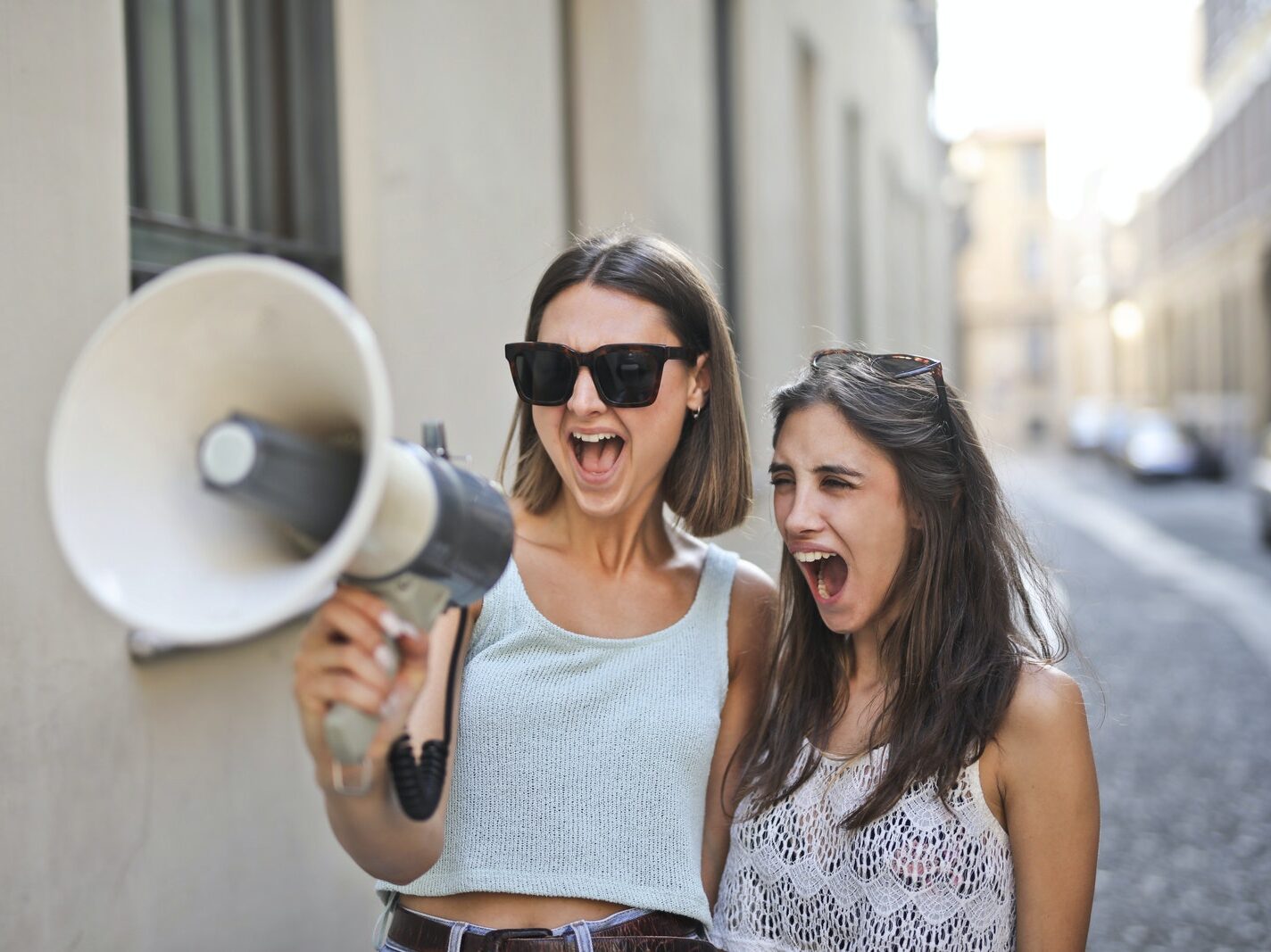 Cheerful young women screaming into loudspeaker