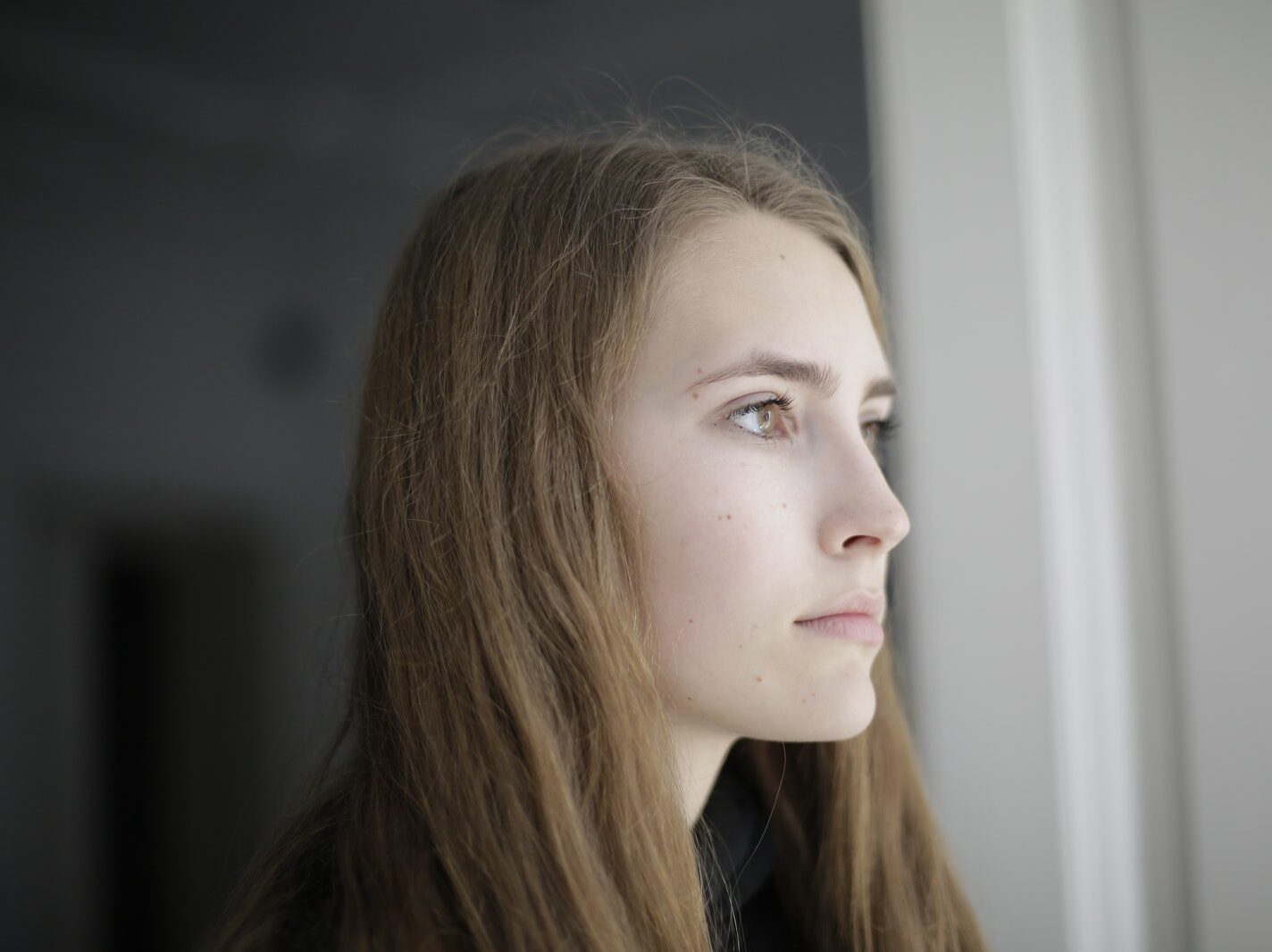 Pensive young woman in living room