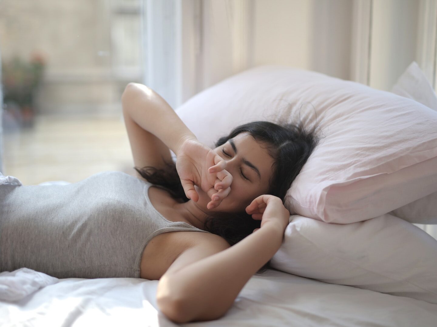 Woman in Gray Tank Top Lying on Bed