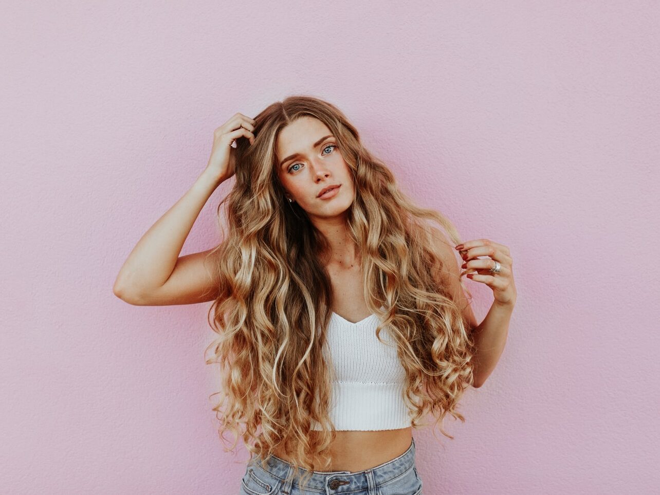 woman standing next to pink wall while scratching her head