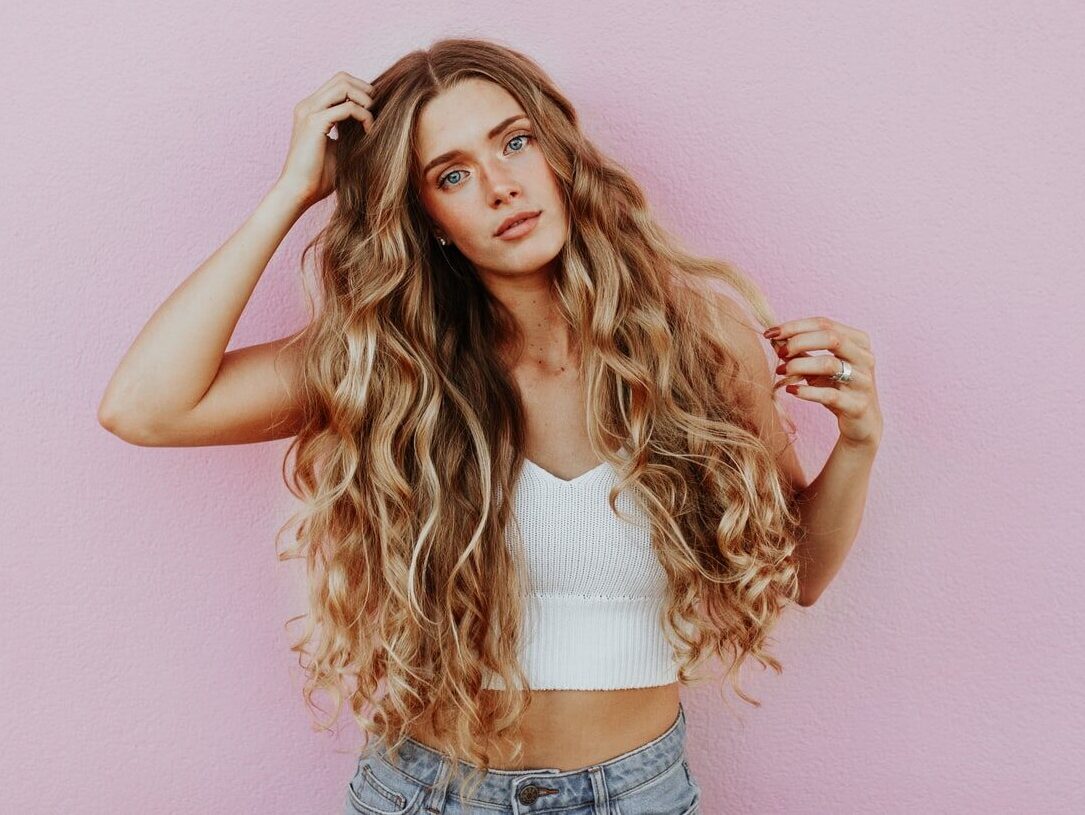 woman standing next to pink wall while scratching her head