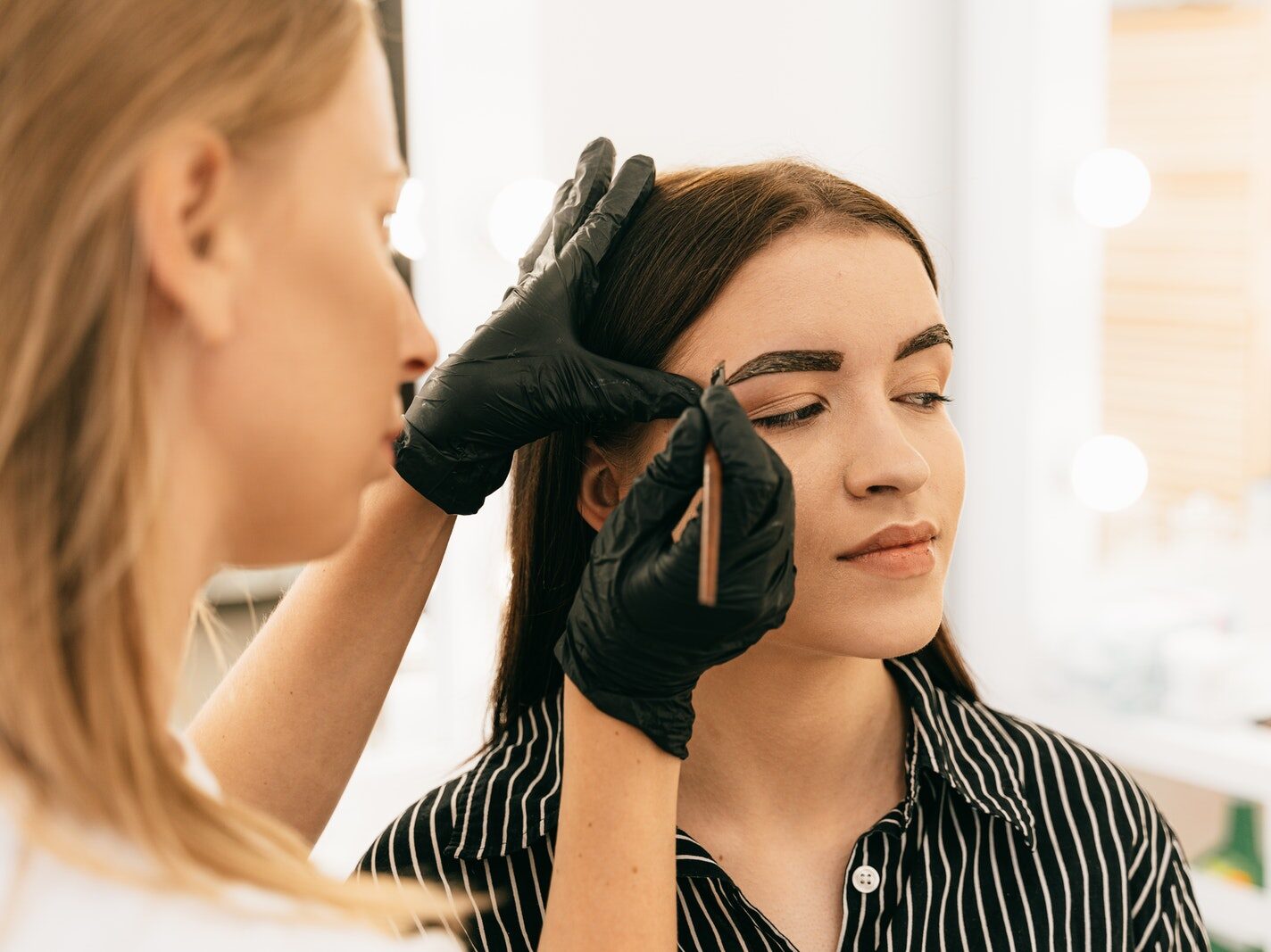 Woman in Black and White Stripe Shirt Getting her Eyebrows Done