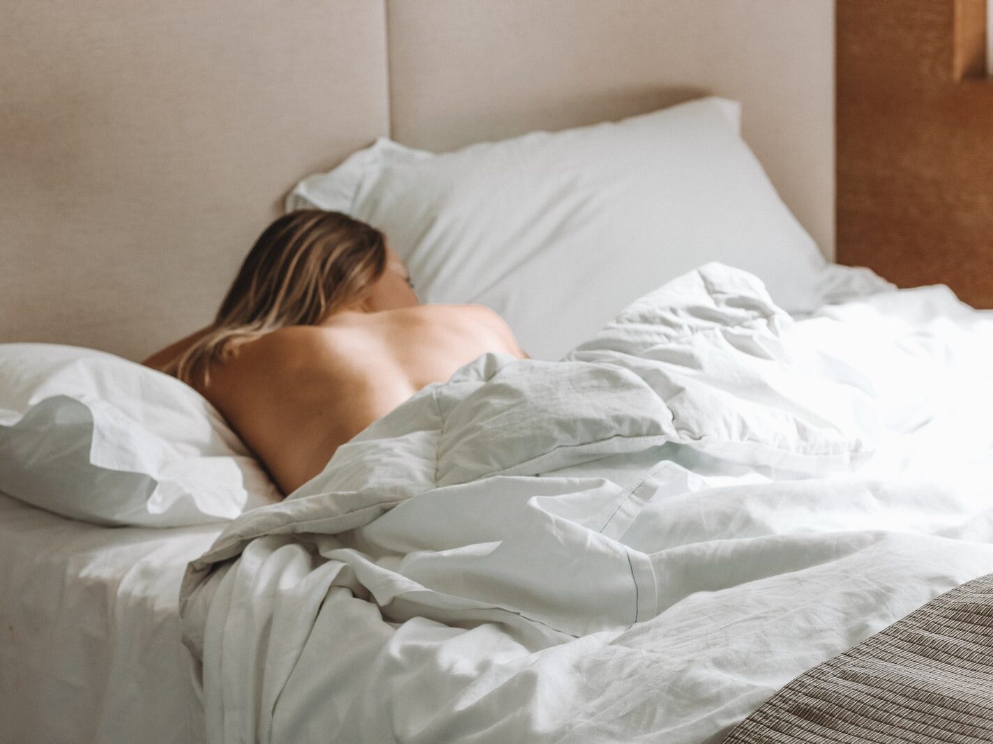 naked woman lying on bed during daytime