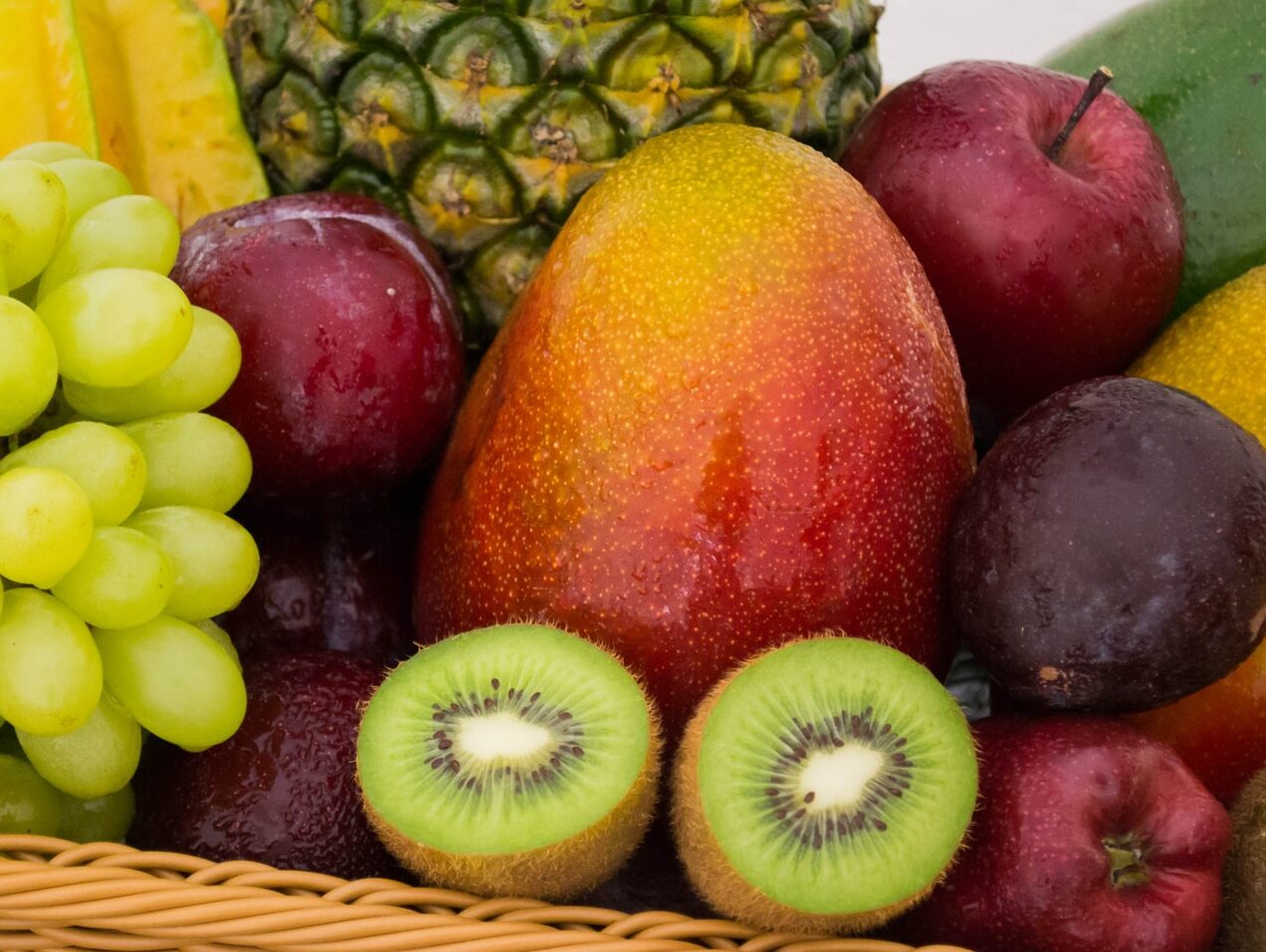 red apple fruit beside green apple and yellow fruit on brown woven basket