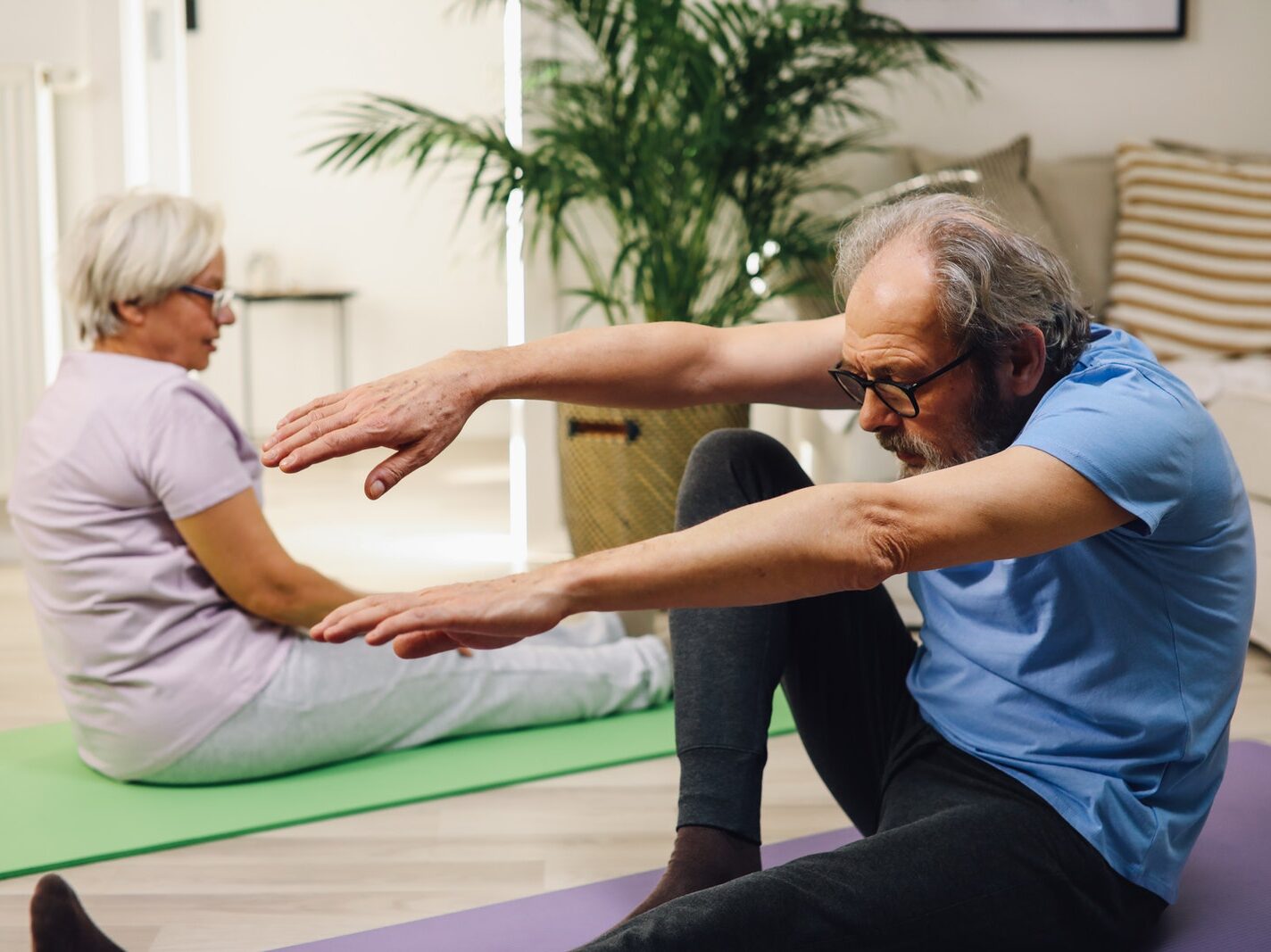 Elderly Couple Sitting on Yoga Mats