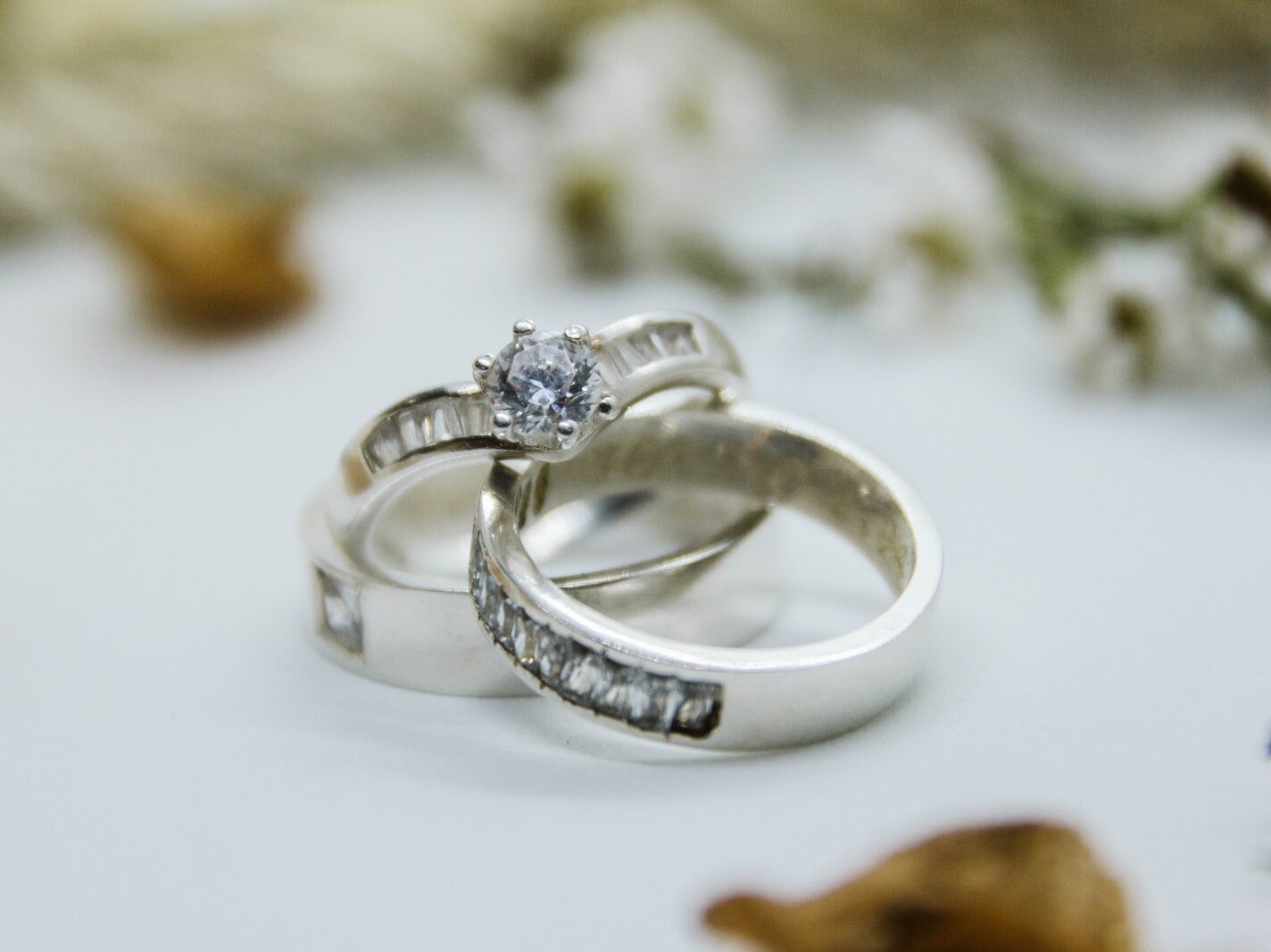silver diamond ring on white surface