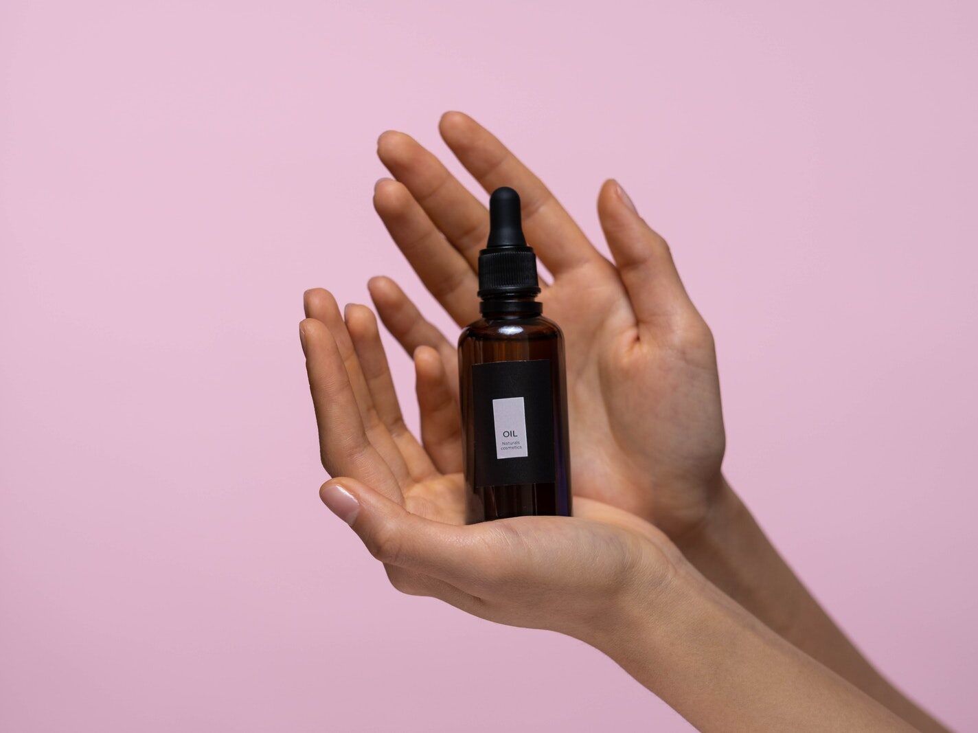 Person Holding A Brown Glass Bottle Of Serum