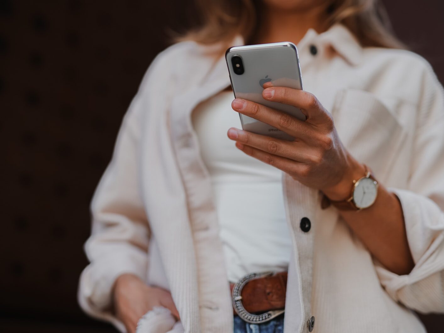 woman in white coat holding silver iphone 6