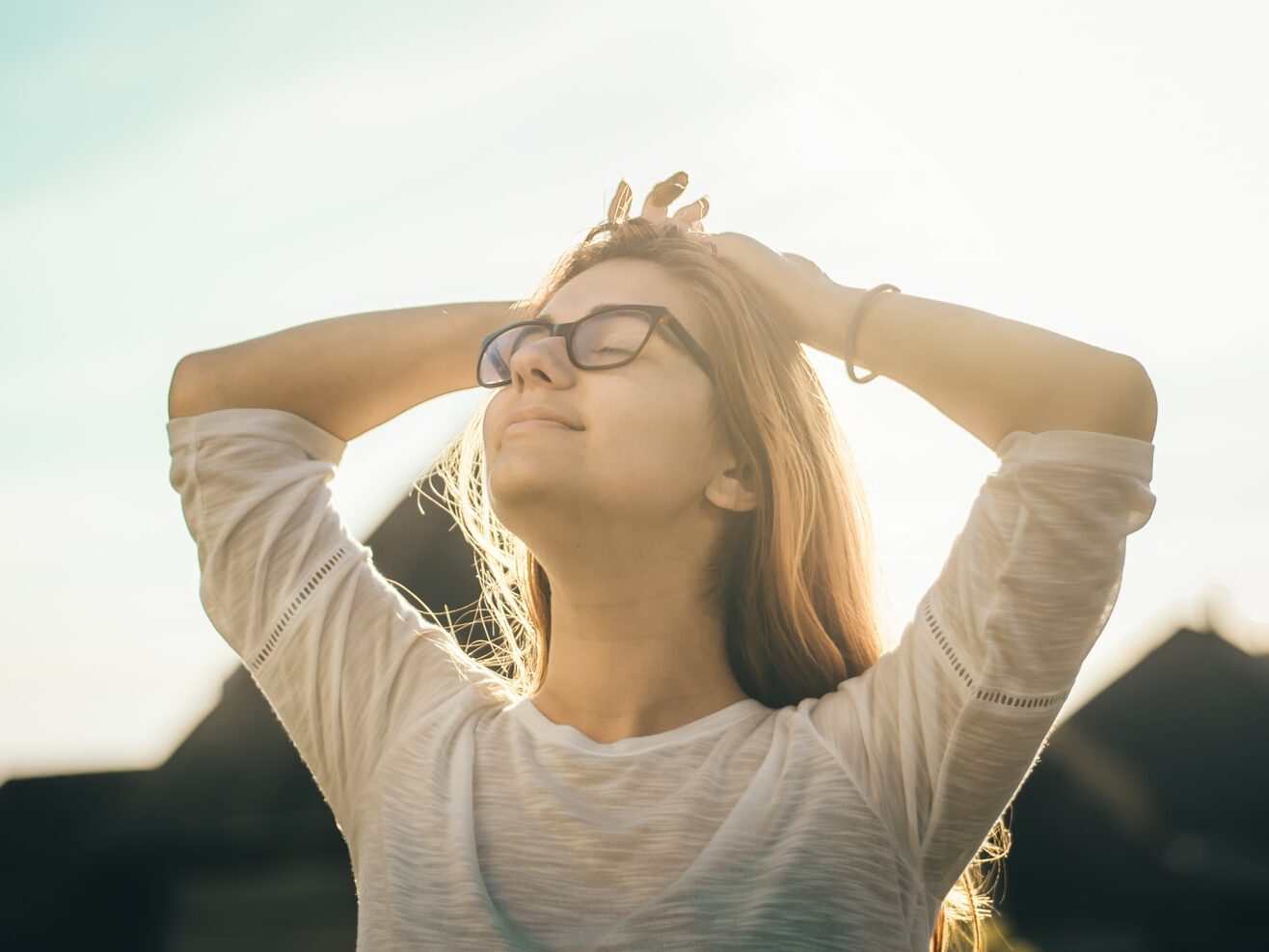 woman in white crew-neck T-shirt holding her head