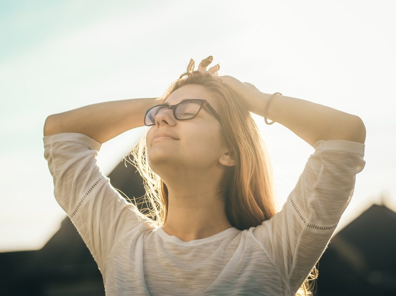 woman in white crew-neck T-shirt holding her head
