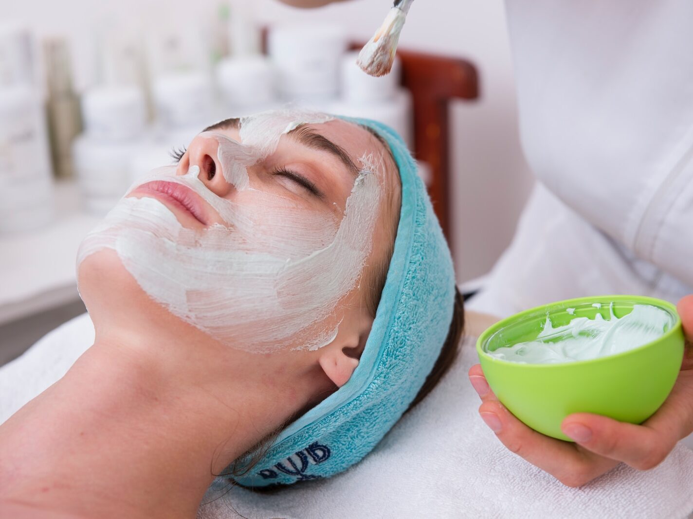 woman lying on blue towel with white cream on face