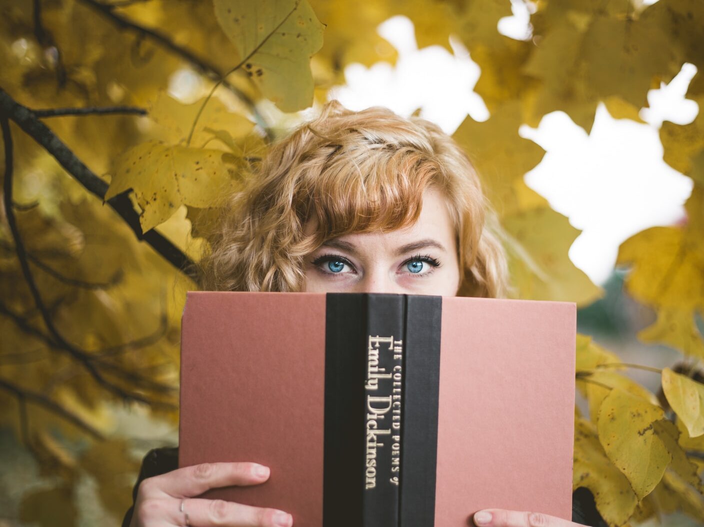 selective focus photography of woman holding Emily Dickinson book