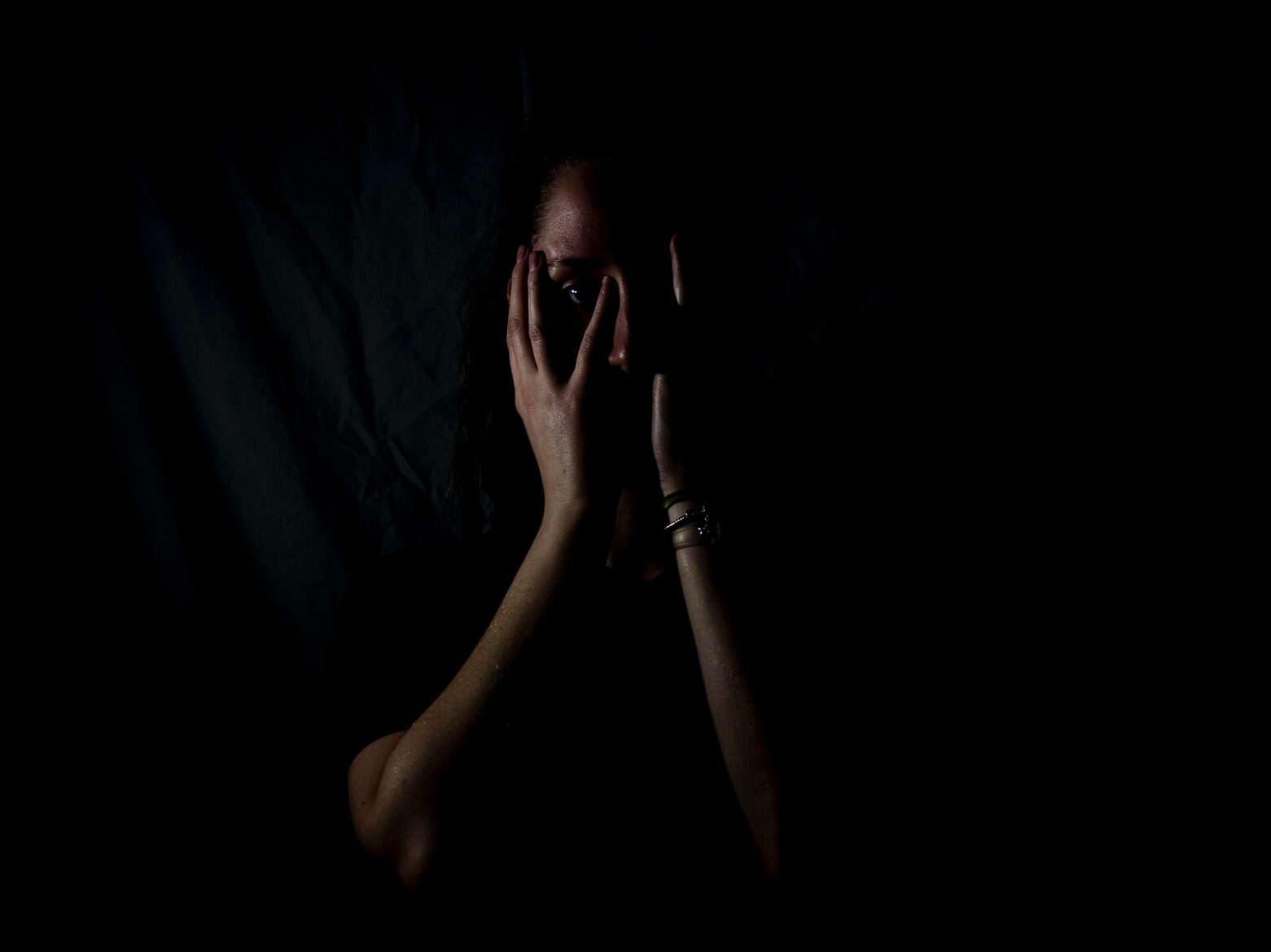 woman holding her face in dark room
