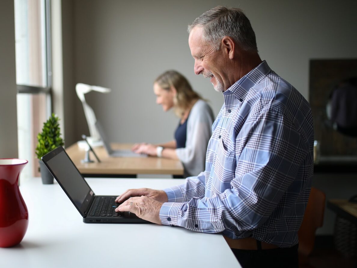man in blue and white plaid dress shirt using black laptop computer
