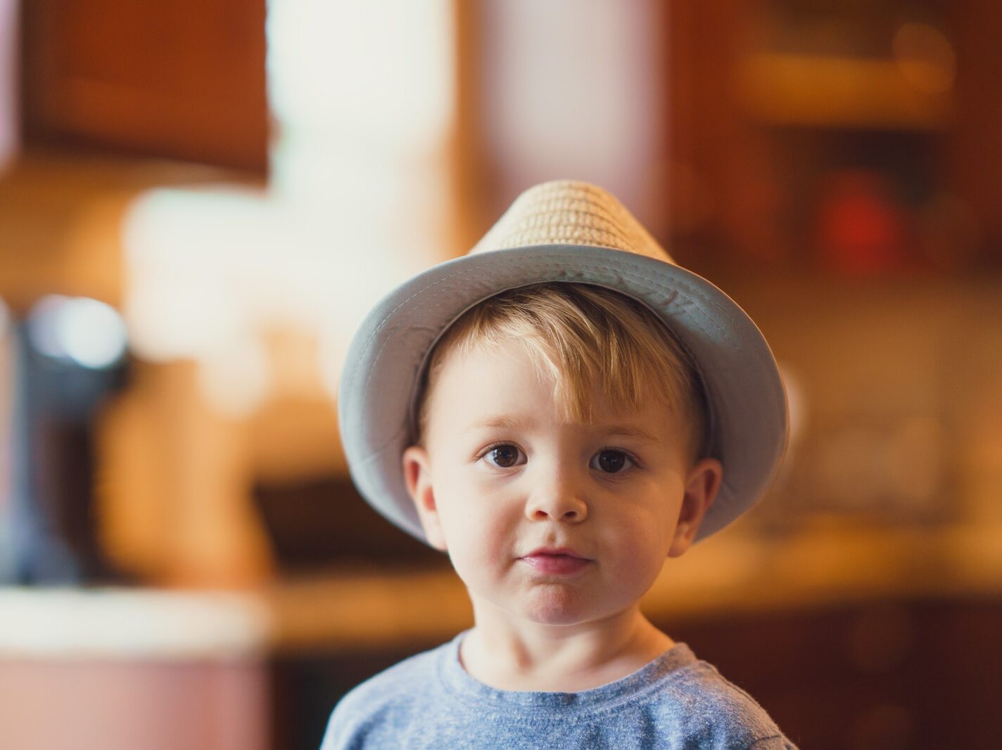 closeup photo of boy wearing brown fedora hat