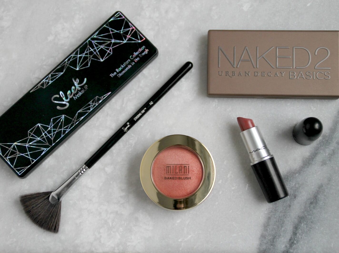 black makeup brush, lipstick, and blush on powder