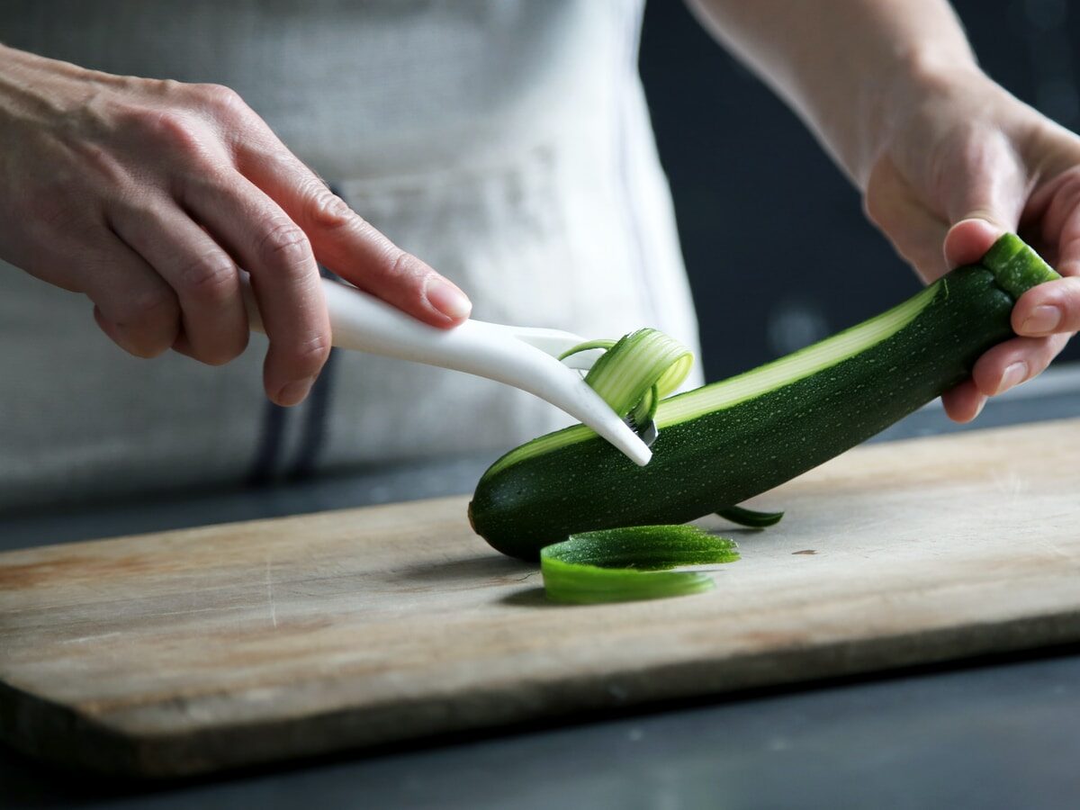 person pealing green cucumber inside room
