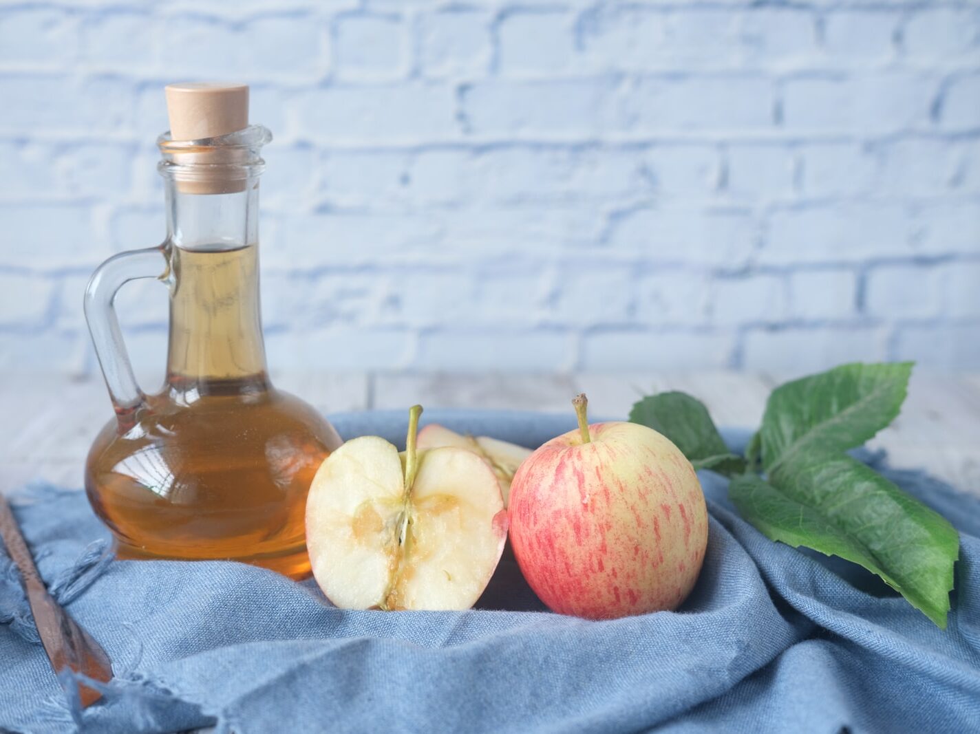 clear glass bottle with red liquid beside sliced lemon on blue textile