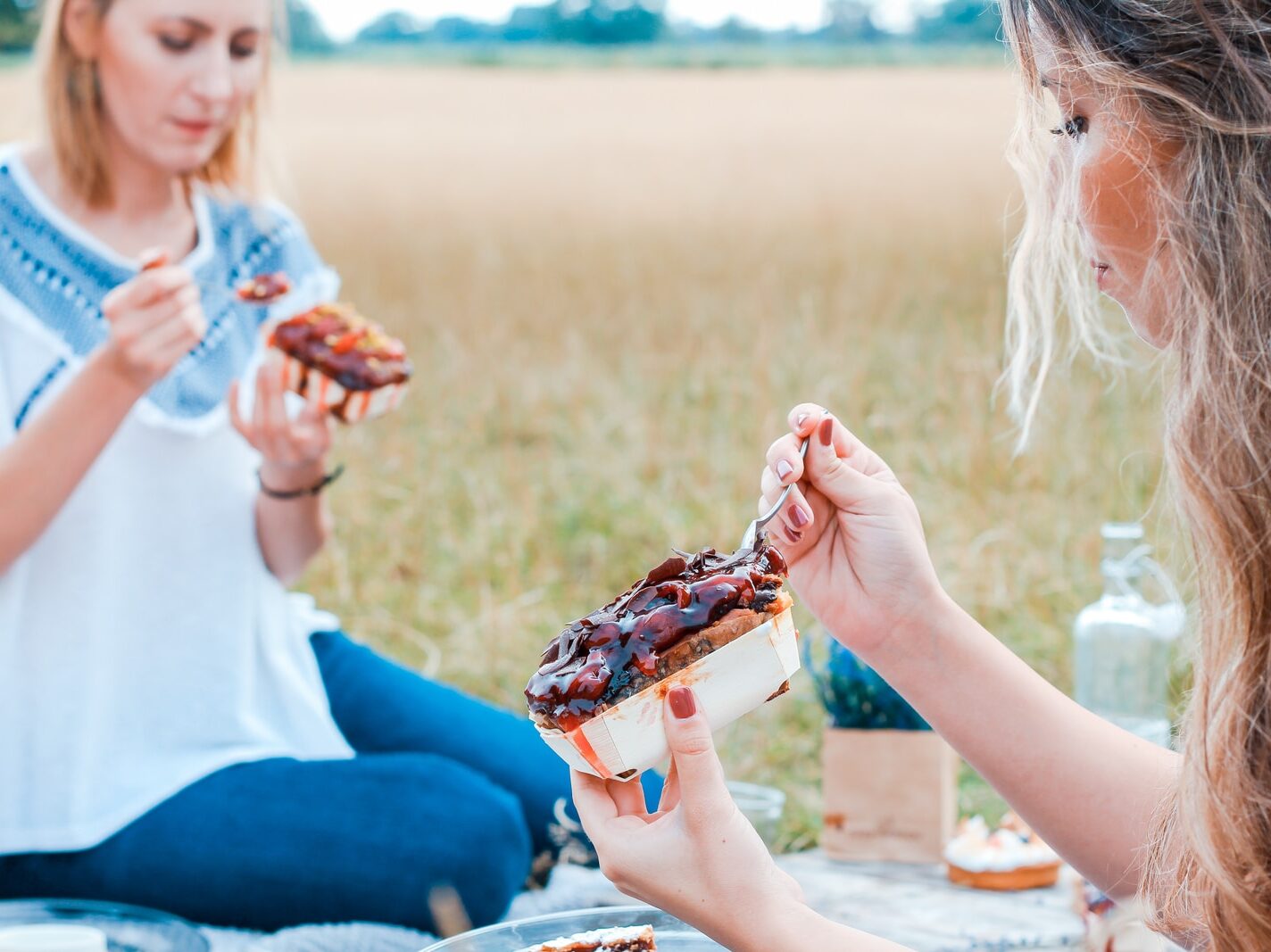 two people eating cake on blue blanket