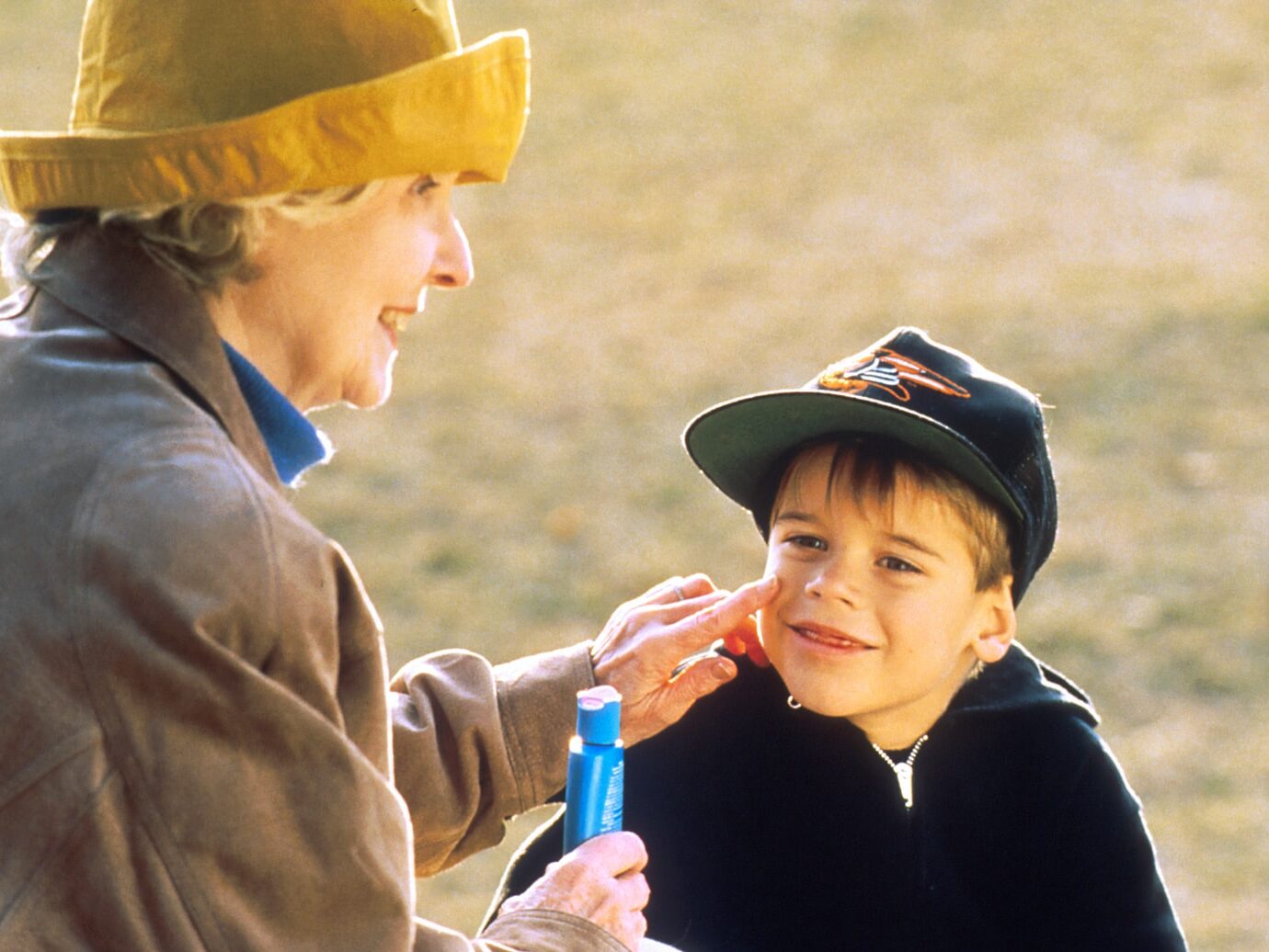 boy in black hat holding blue plastic bottle