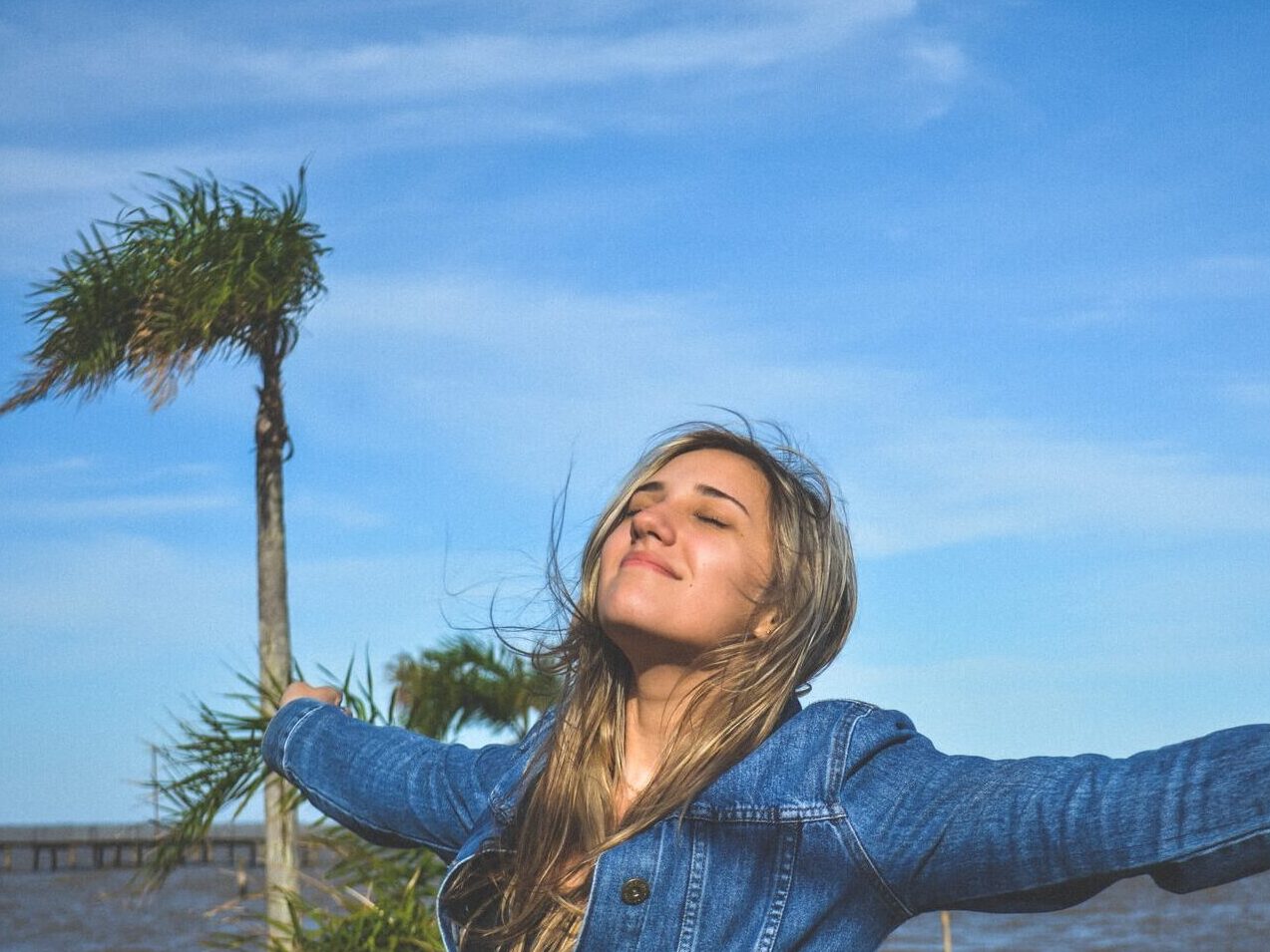 woman spreading arms near body of water