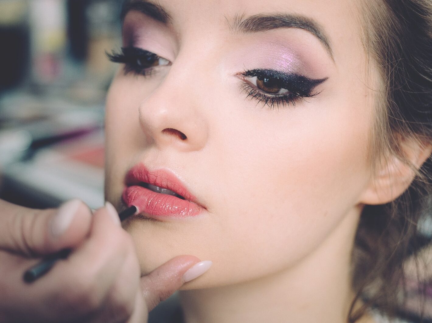woman getting lips applied with lipstick