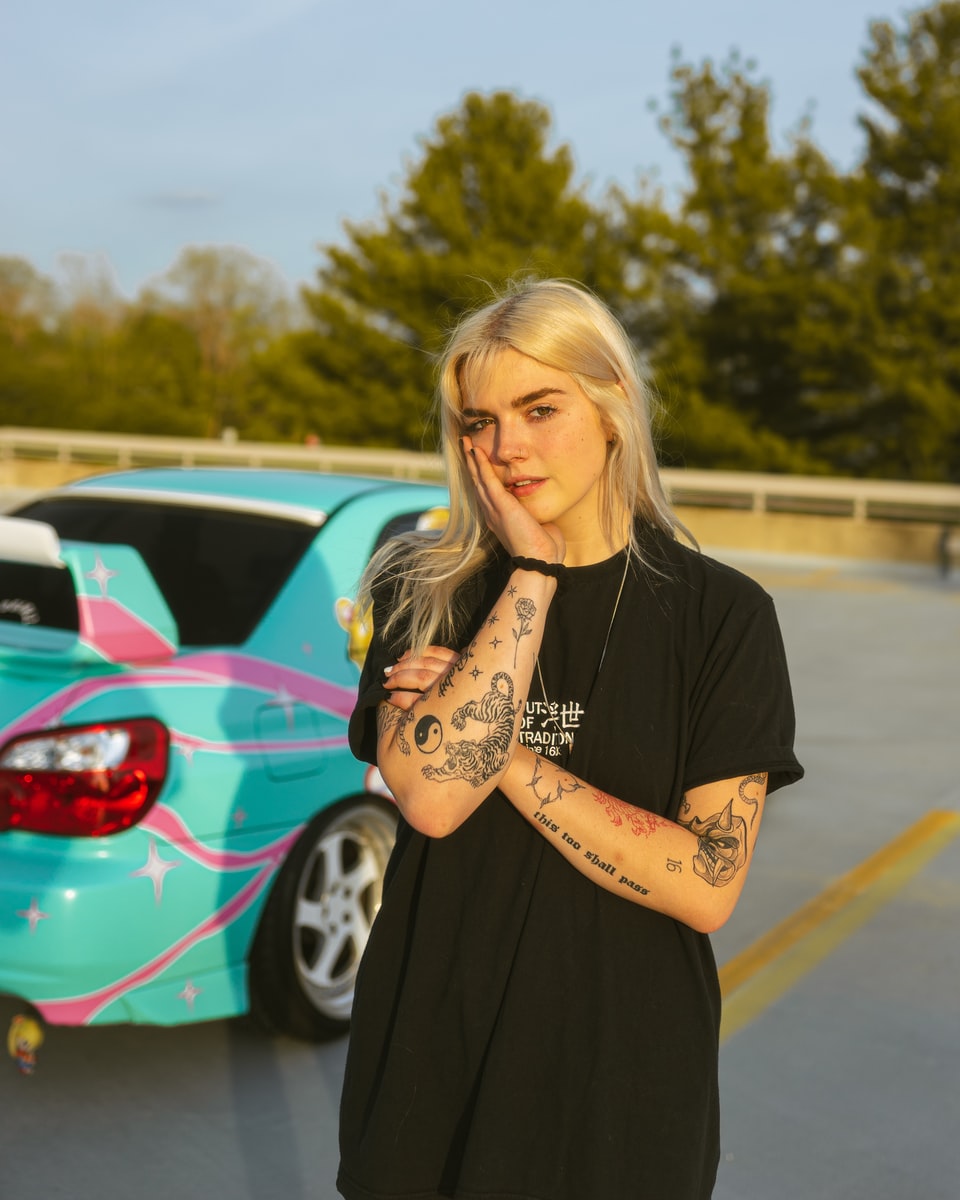 woman in black shirt standing near red car during daytime