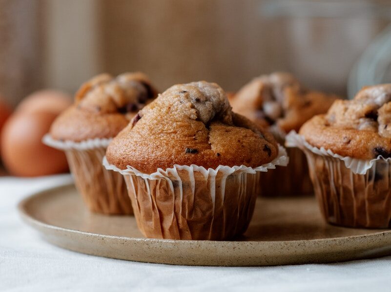 Tasty muffins with chocolate chips on plate
