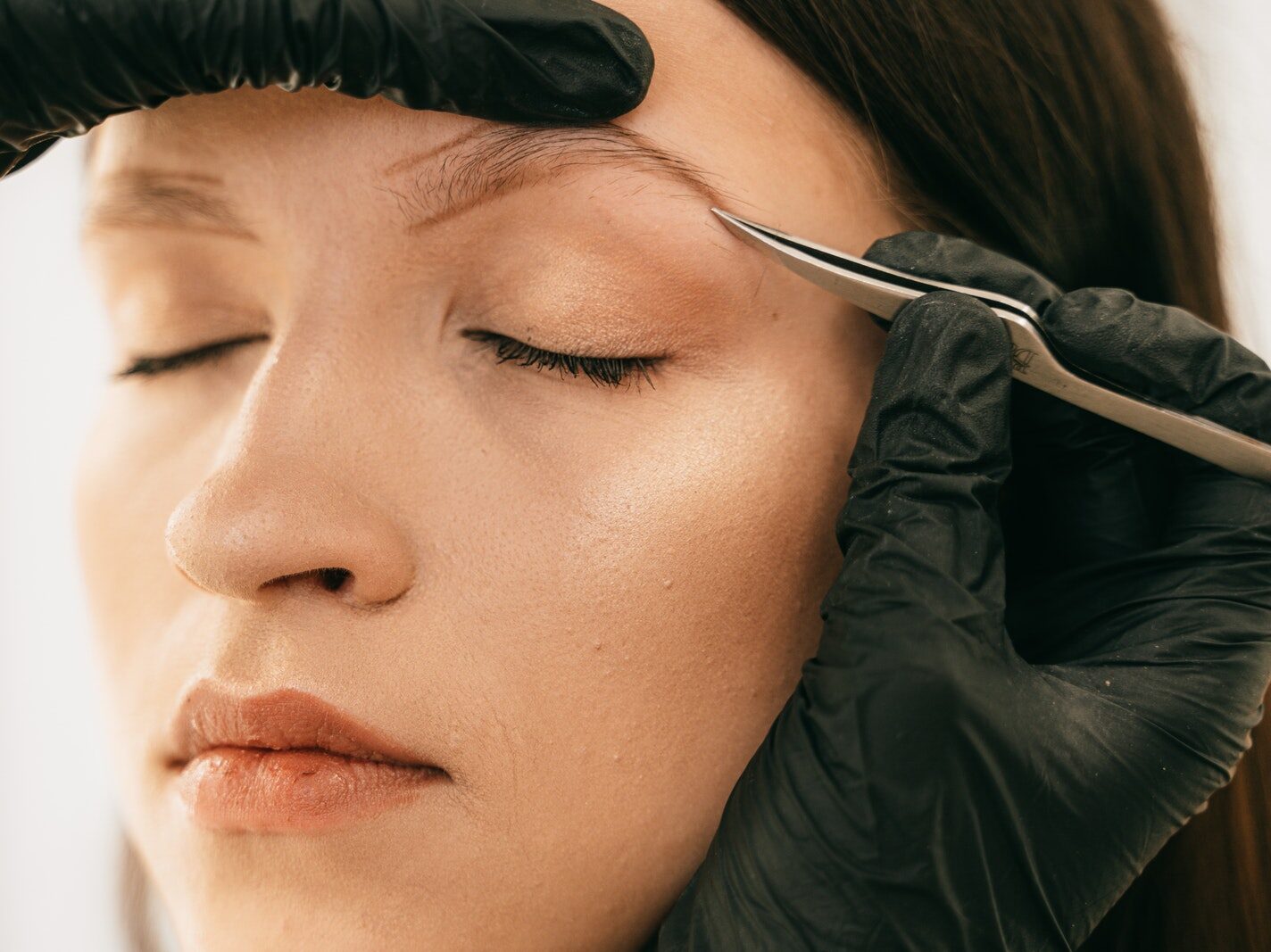 Person Plucking Woman's Eyebrow