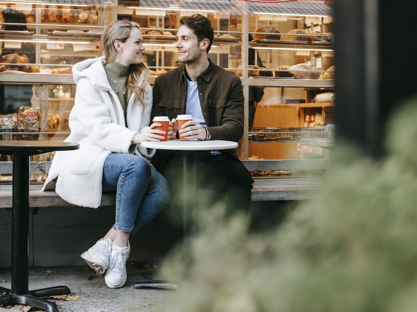 Happy young man and woman having hot tea in cosy cafe