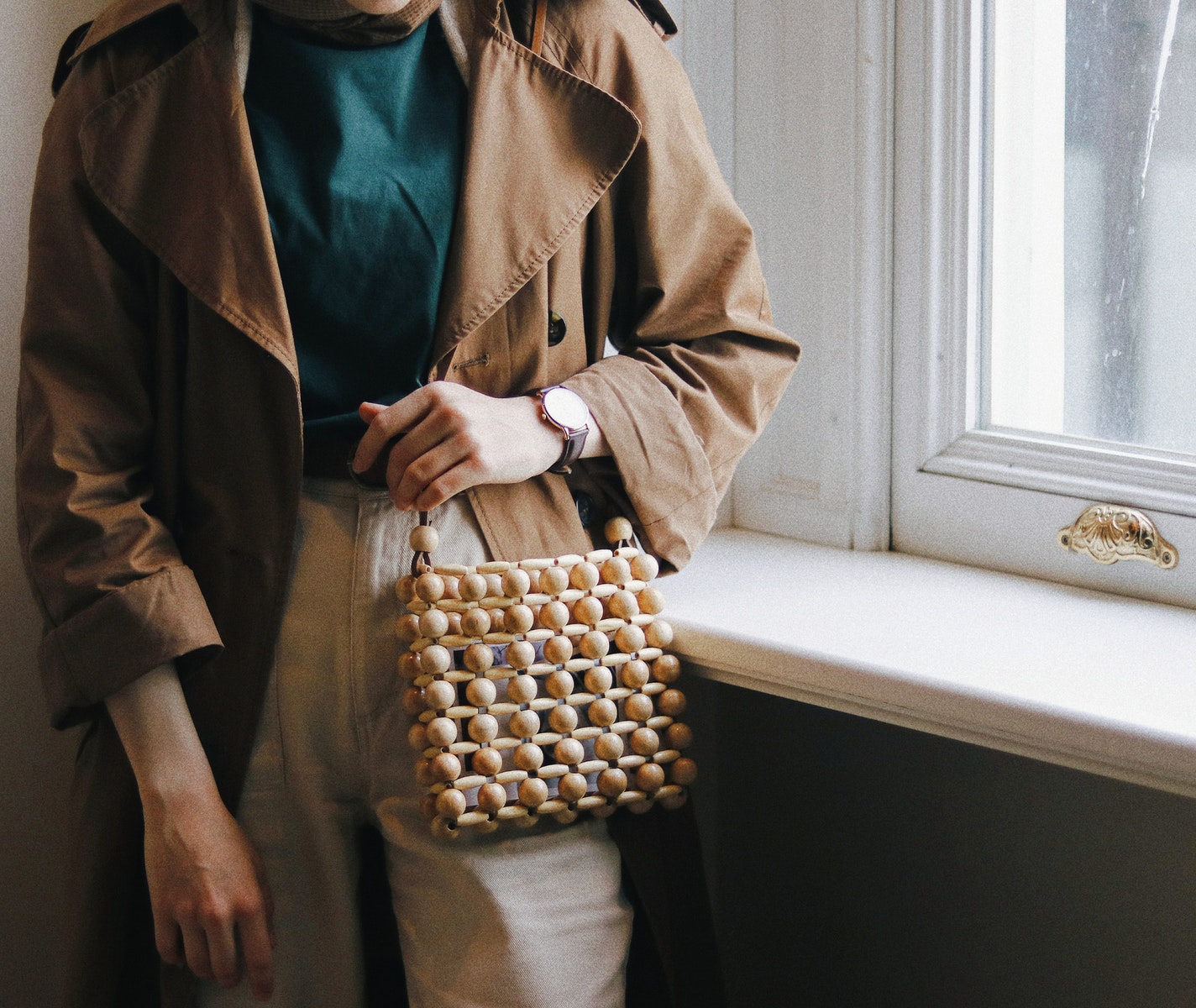 Crop stylish woman with handbag against window