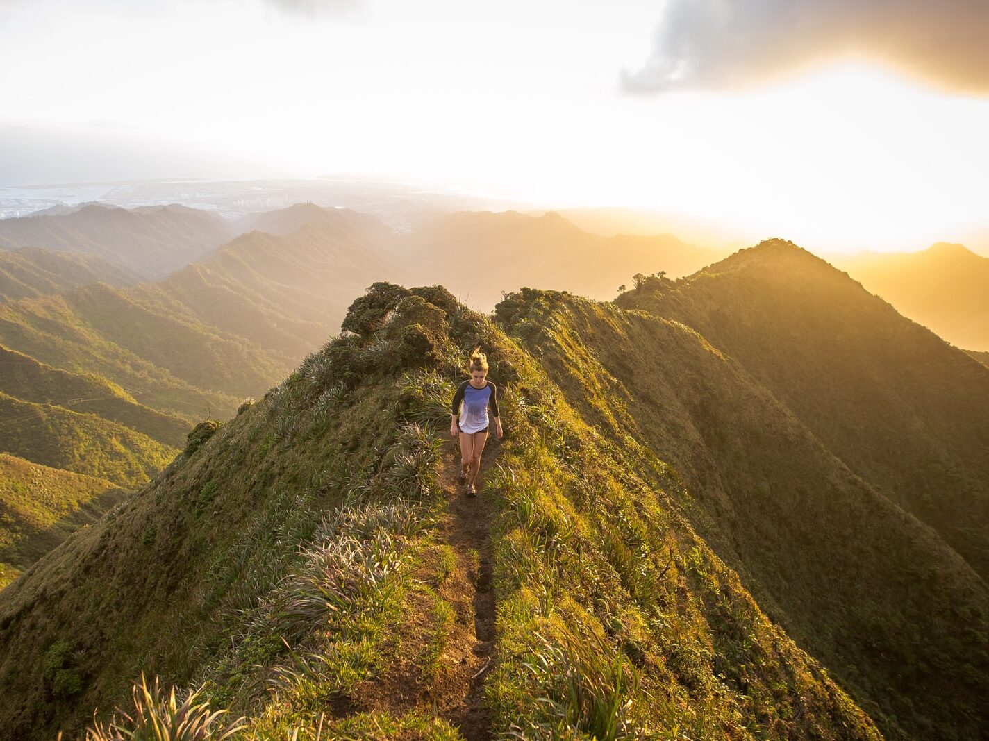 woman walking on pathway on top of hill at golden hour
