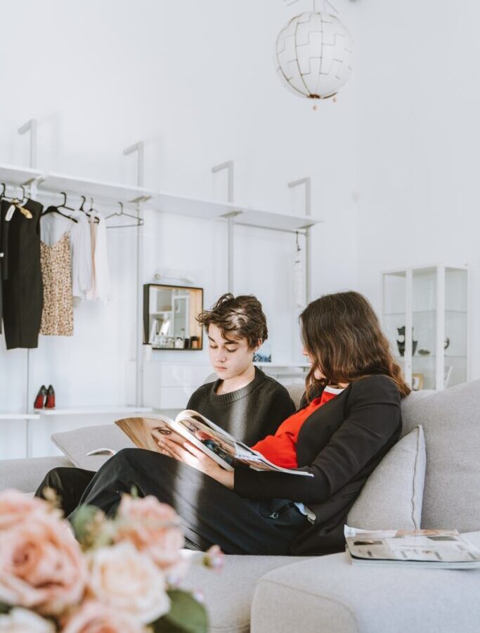 Young Man and Woman Sitting on a Couch Reading Magazine