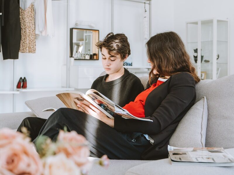 Young Man and Woman Sitting on a Couch Reading Magazine