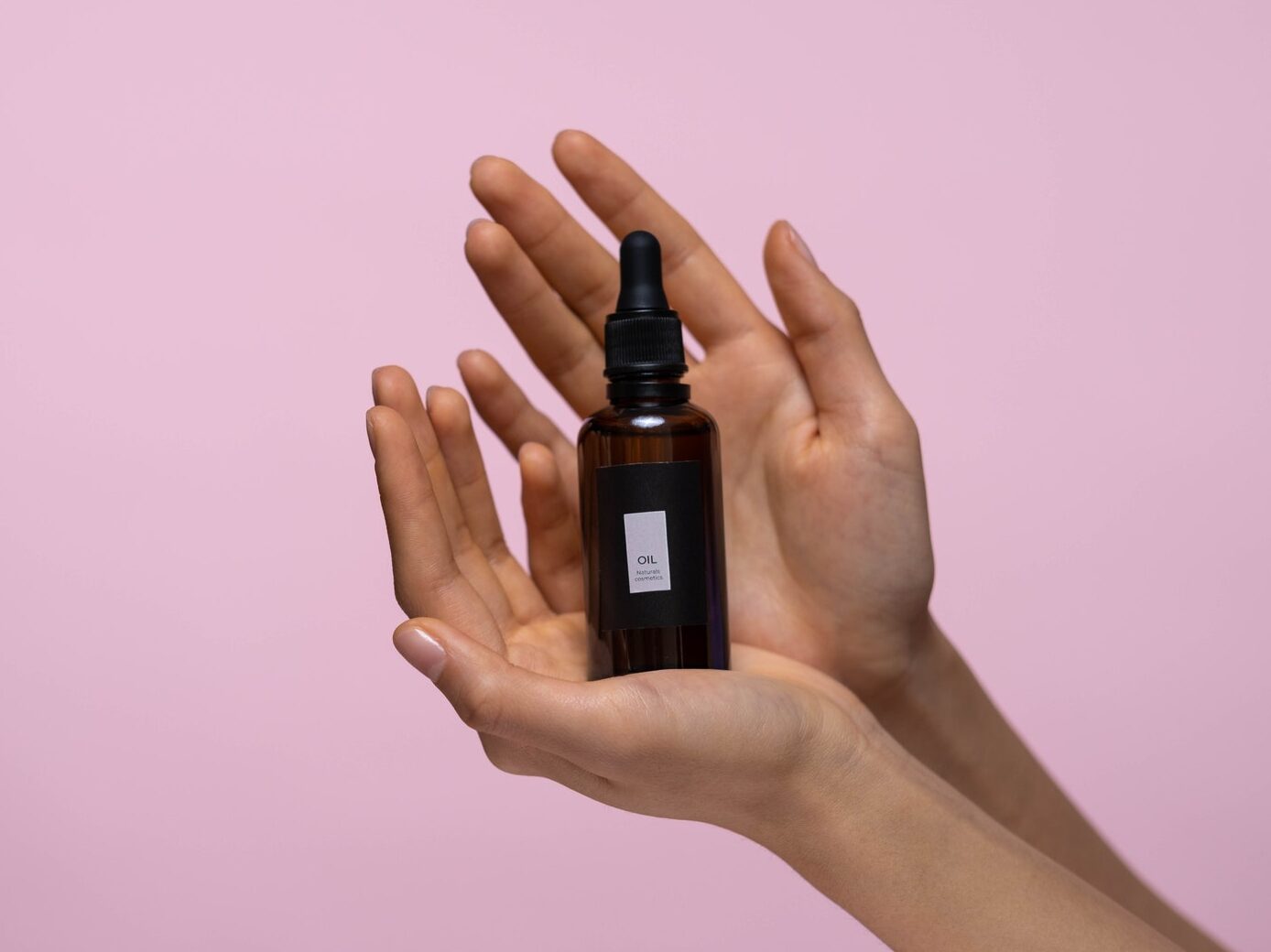 Person Holding A Brown Glass Bottle Of Serum