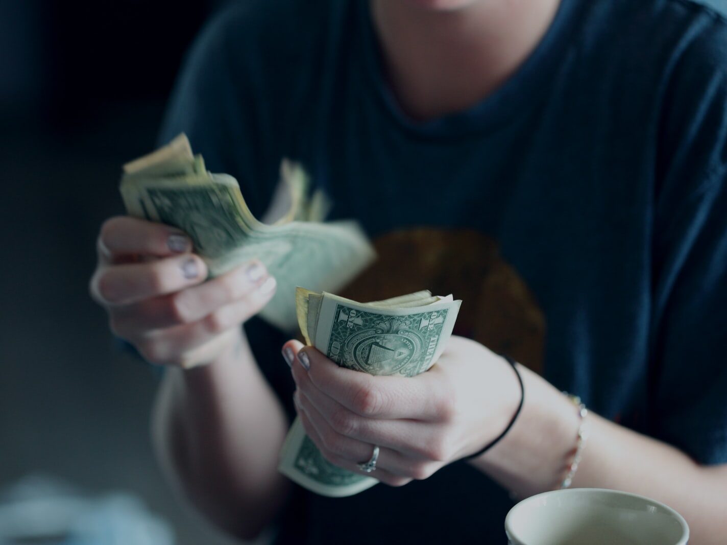 focus photography of person counting dollar banknotes